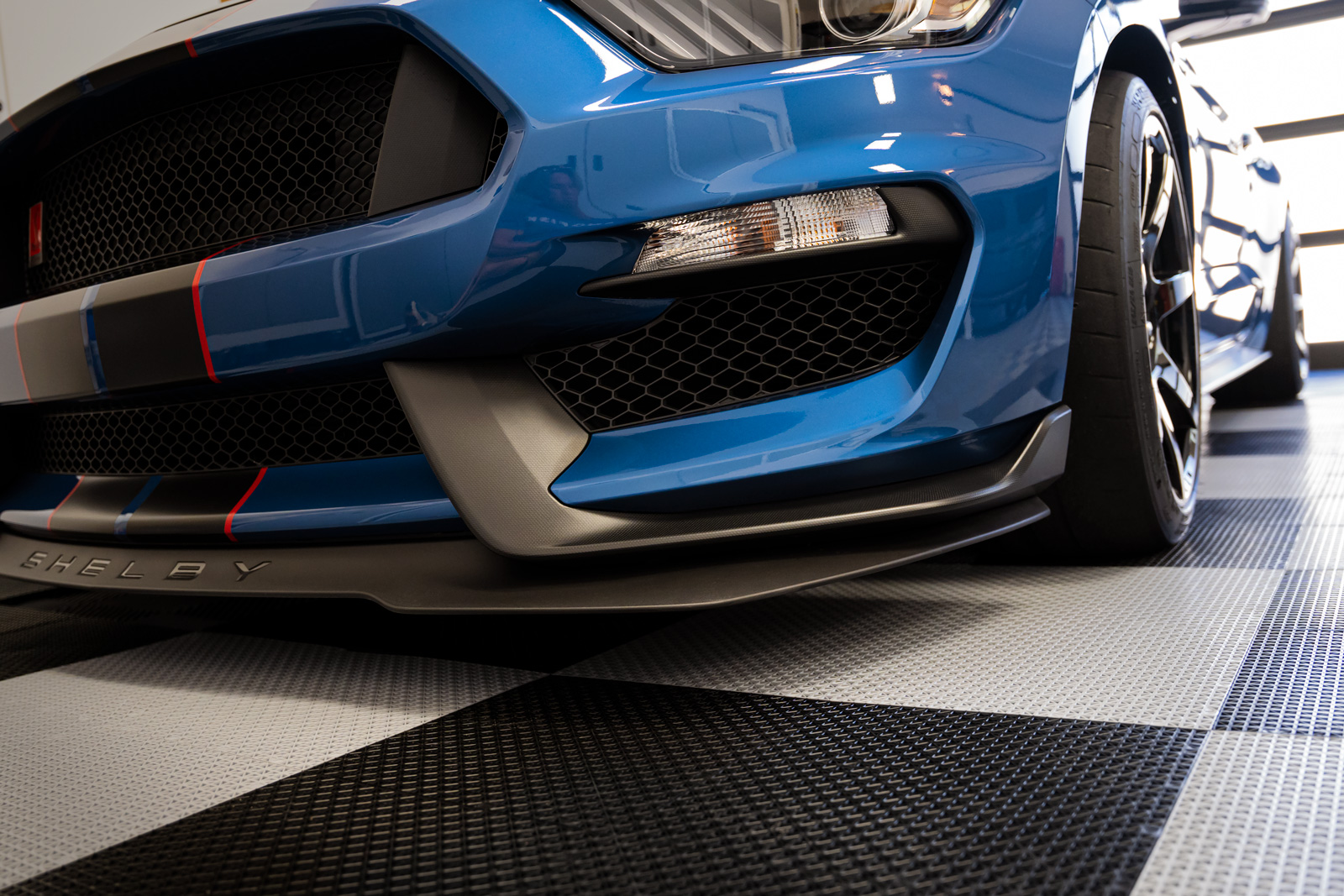 RaceDeck interlocking garage floor tiles installed under a Ford Mustang