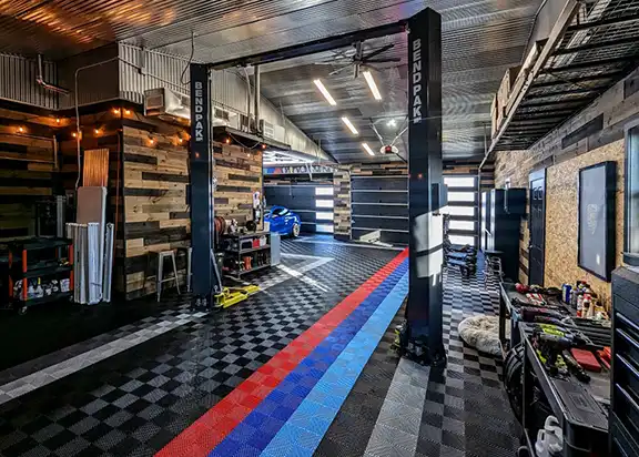 A well designed garage with wood paneling, a Benpak lift and RaceDeck Free-Flow flooring.