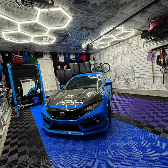 A blue Honda Civic Type R parked in a clean garage with hexlights and a RaceDeck floor.