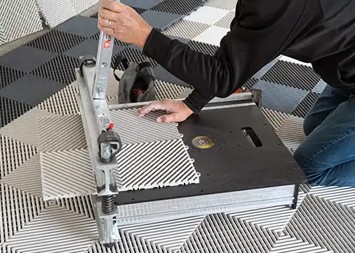 An old man cuts tiles with a magnum shear.
