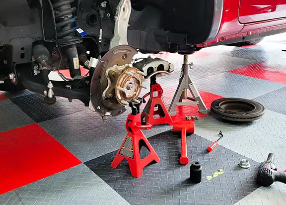 A car on jack stands with the wheel and rooter removed.