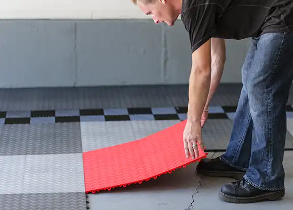 A man installs a section of RaceDeck Diamond garage flooring
