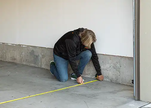 An old man measures his daughter's garage with a tape measure before installing her garage floor.